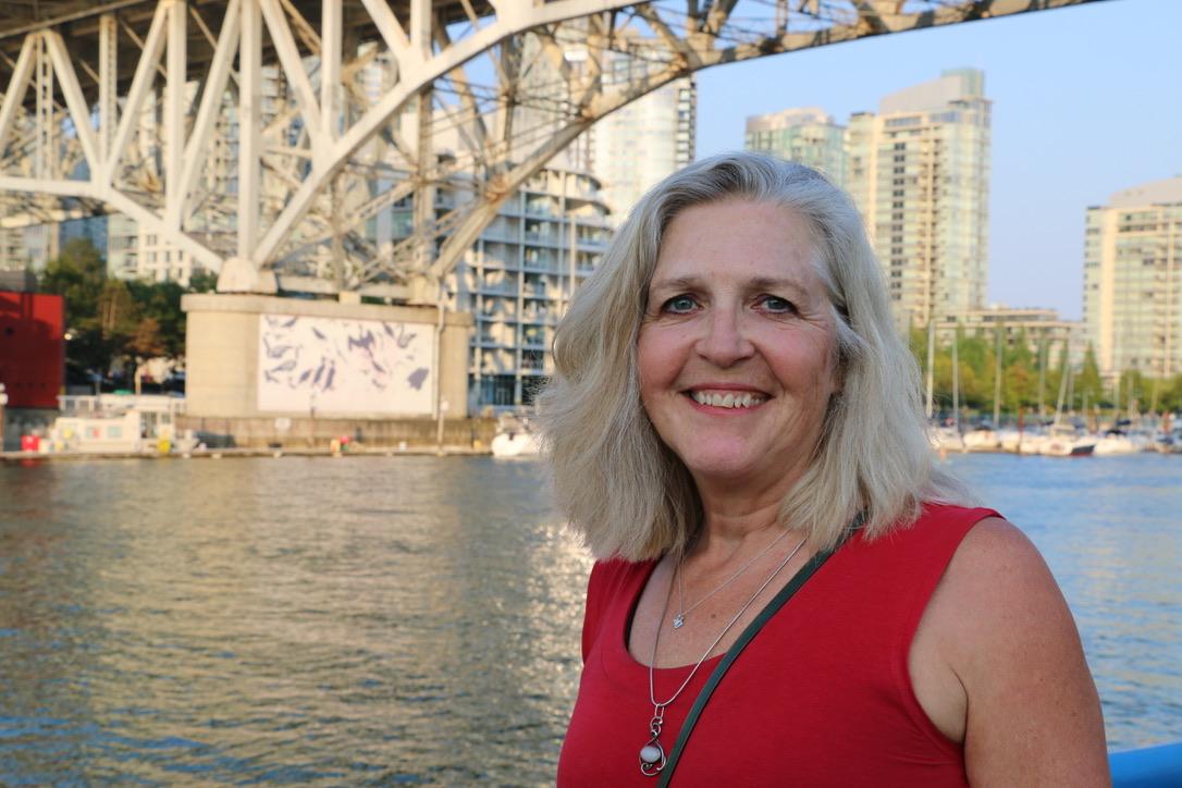 Smiling woman at an urban waterfront.
